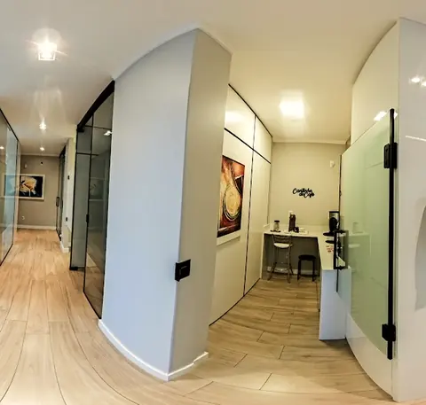Corredor com divisórias de vidro e o cantinho do café ao fundo