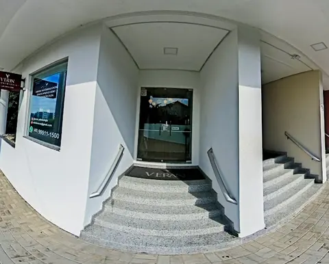 Fachada branca da VERAN Odontologia com escada de granito e placa vinho na entrada